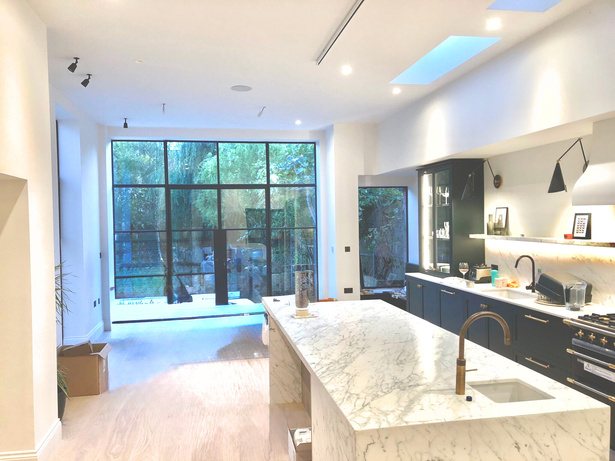 Dark kitchen with Crittall doors opening to the garden and a marble island